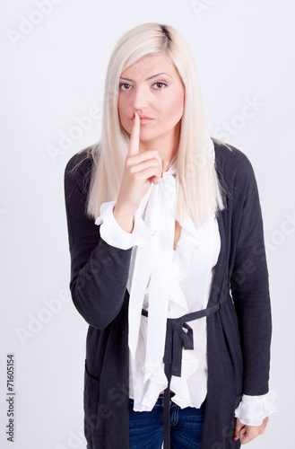 Young woman with finger on lips over white background