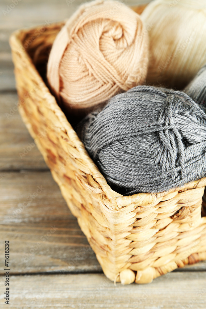 Obraz premium Knitting yarn in basket, on wooden background