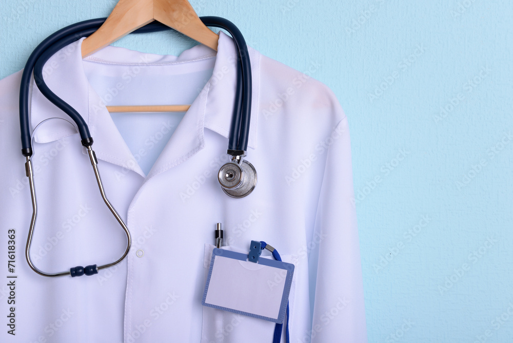 Doctor coat with stethoscope on hanger on blue background Doctor coat with stethoscope on hanger on blue background