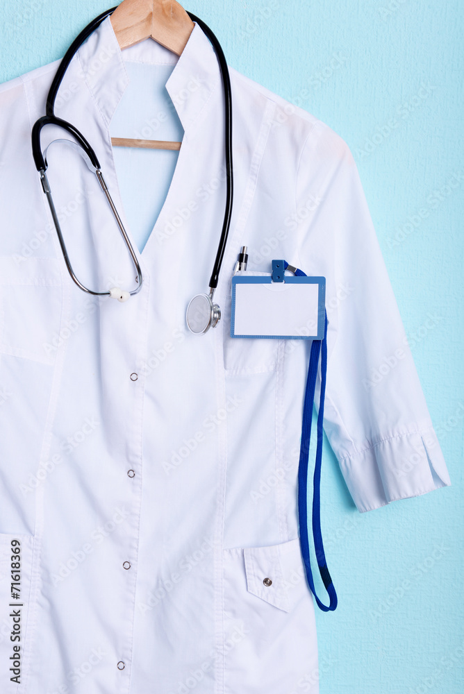 Doctor coat with stethoscope on hanger on blue background