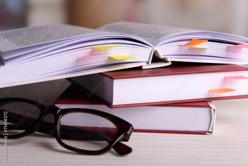 Books with bookmarks and glasses on table on bright background Books with bookmarks and glasses on table on bright background