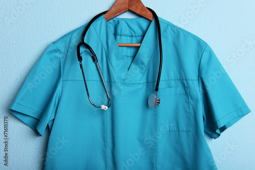 Doctor shirt with stethoscope on hanger on blue background