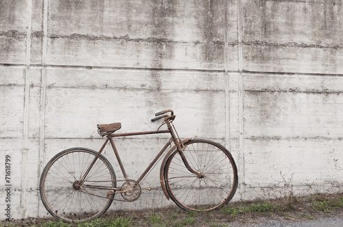 Antique or retro oxidized bicycle outside on a concrete wall © irantzuarb