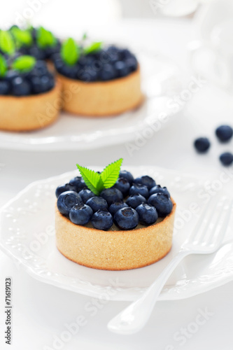 Tartlets with cream and blueberries, selective focus