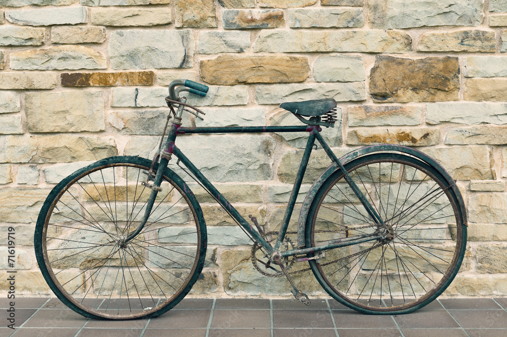 Antique or retro oxidized bicycle outside on a stone wall Antique or retro oxidized bicycle outside on a stone wall