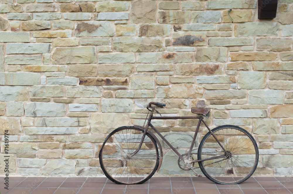 Antique or retro oxidized bicycle outside on a stone wall Antique or retro oxidized bicycle outside on a stone wall