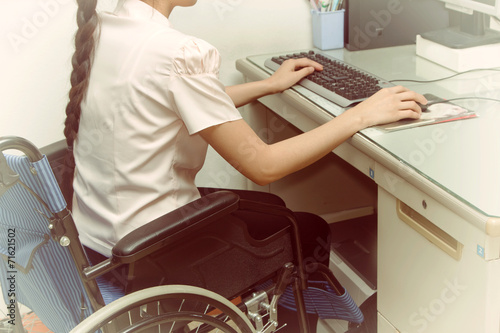 Asia woman in wheelchair working on computer in the office photo