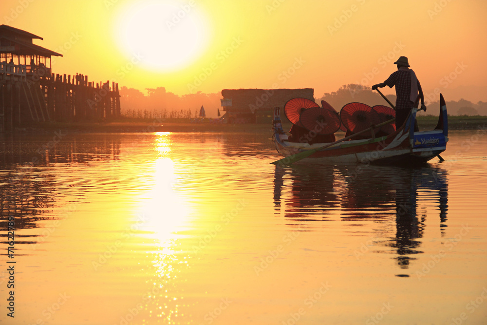 Burmese boatman and buddhist novice sitting in boat