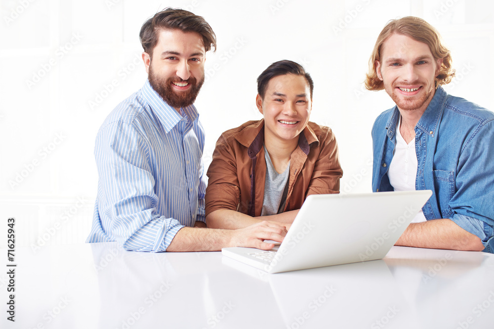 Fototapeta premium Three handsome young men using a laptop