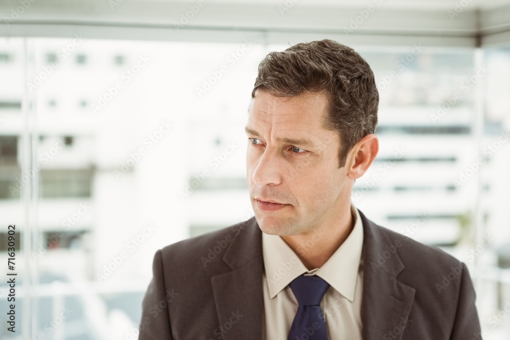 Thoughtful businessman looking away at office Thoughtful businessman looking away at office