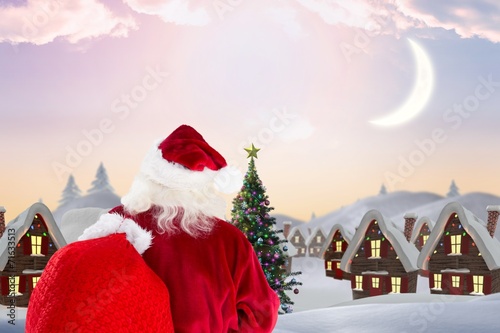 Composite image of santa claus carrying sack photo