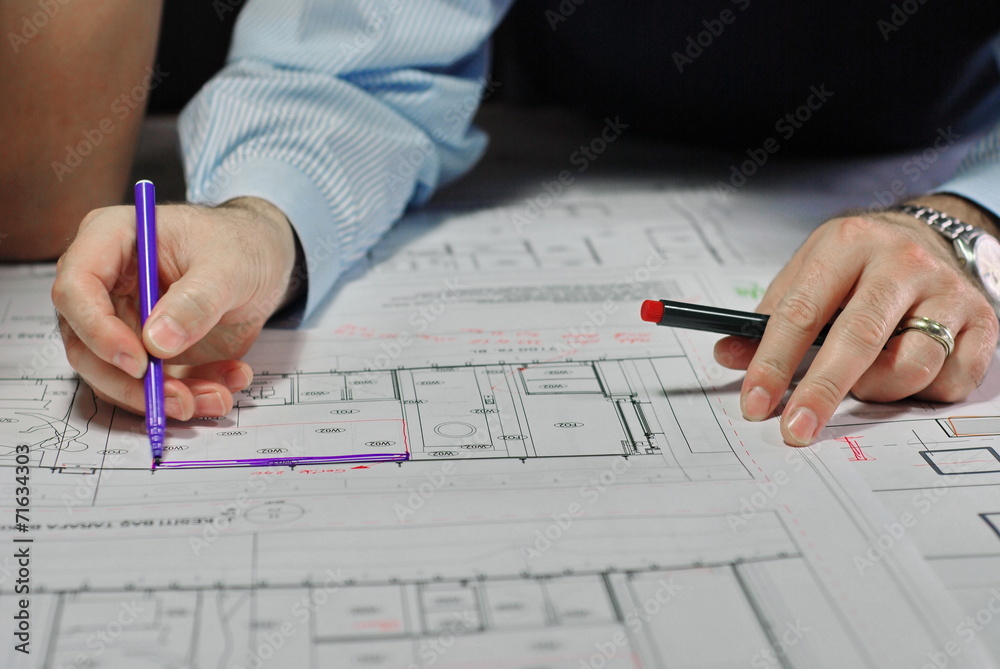 Architects Discussing Plan Together At Desk Architects Discussing Plan Together At Desk