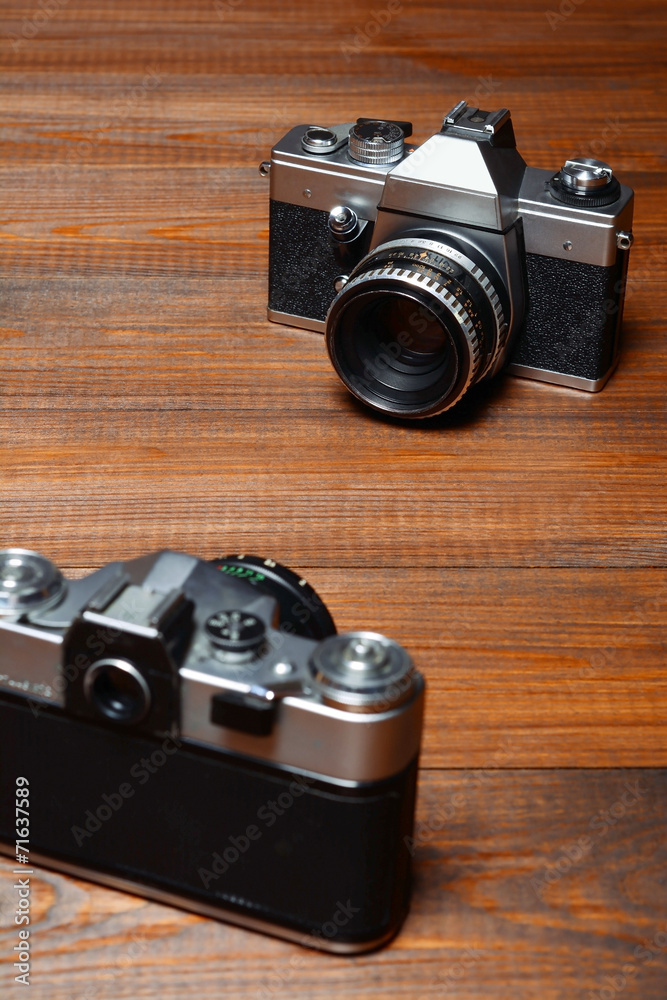 Two old cameras on wooden background.