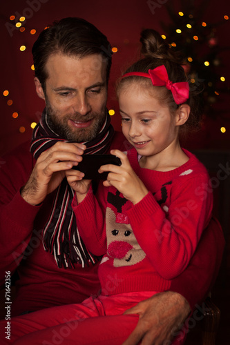 Christmas - father and daughter playing game on mobile phone