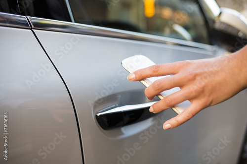 Woman opening car with her ​​mobile phone