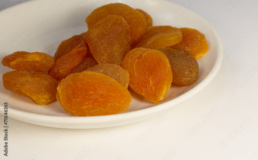 Dried apricots on a white plate on a white background