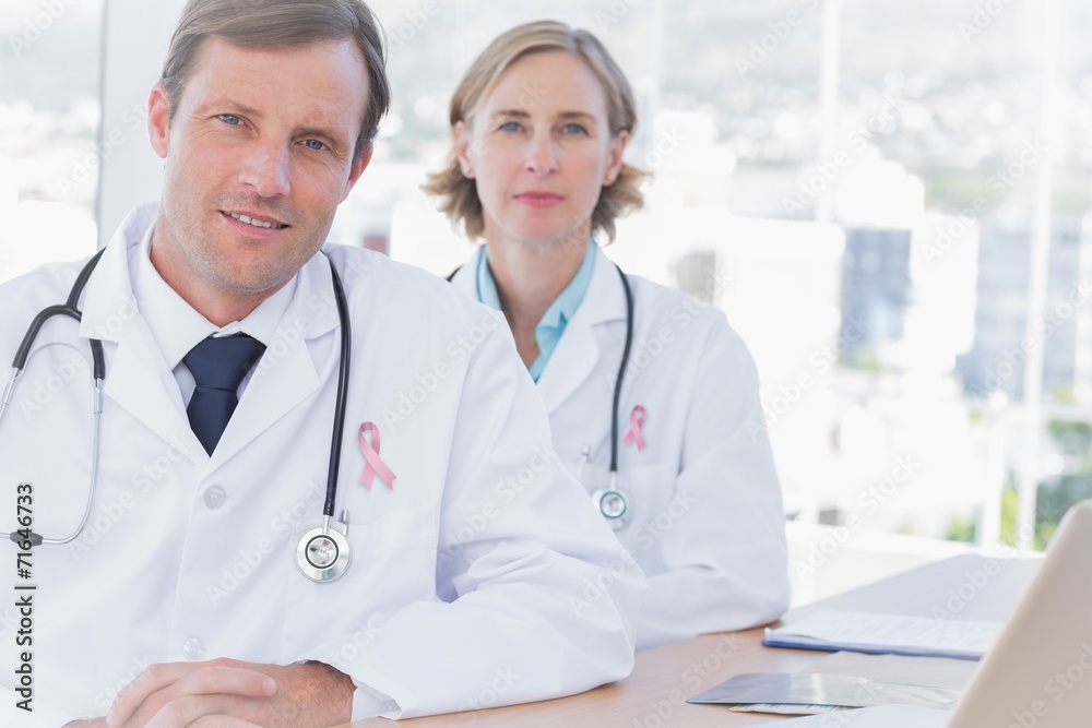 Composite image of group of doctors posing at their desk Composite image of group of doctors posing at their desk