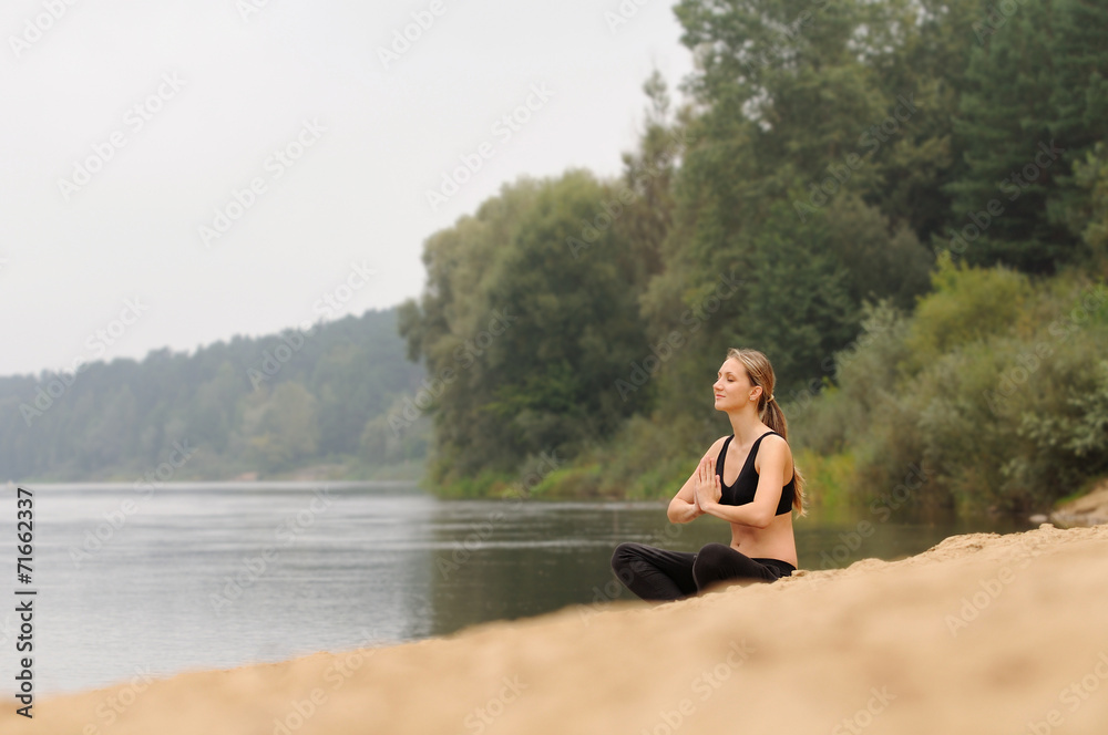 young beautiful woman practicing yoga at forest lake