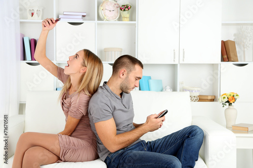 Young couple after quarrel sending to each other messages at