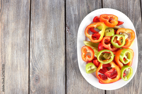 Sliced pepper on oval plate on wooden background