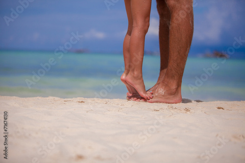 Little girl and her father feet at white sandy beach