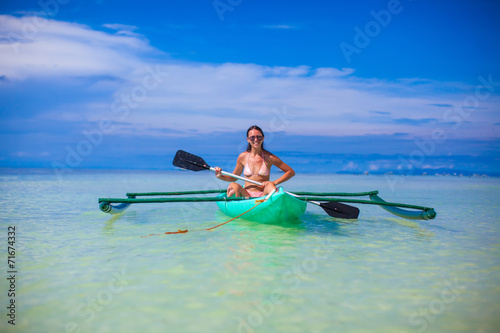 Young woman kayaking alone in the clear blue sea