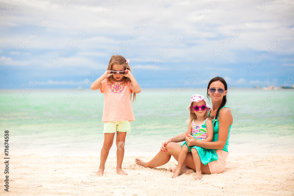 Beautiful mother and her little daughters at exotic beach