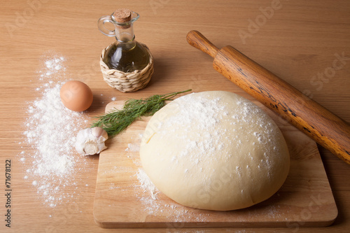 dough on a board with flour. olive oil, eggs, rolling pin, garli
