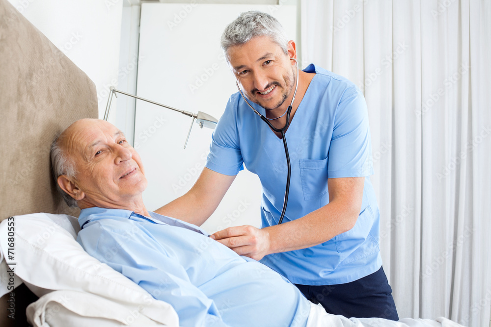 Fototapeta premium Portrait Of Smiling Caretaker Examining Senior Man