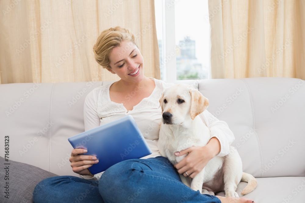 Happy blonde using tablet pc with puppy Happy blonde using tablet pc with puppy