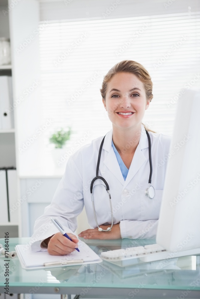 Doctor smiling as she takes notes Doctor smiling as she takes notes