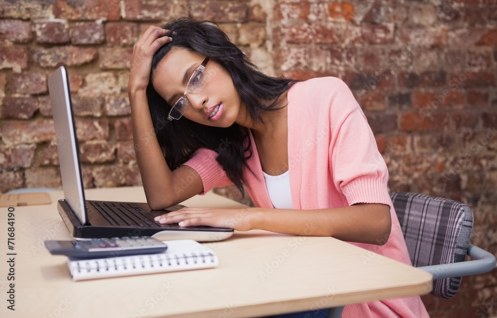Troubled woman sitting at her desk with a laptop Troubled woman sitting at her desk with a laptop