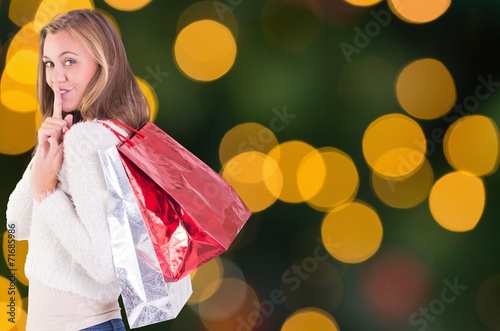 Composite image of pretty blonde keeping a secret holding bags