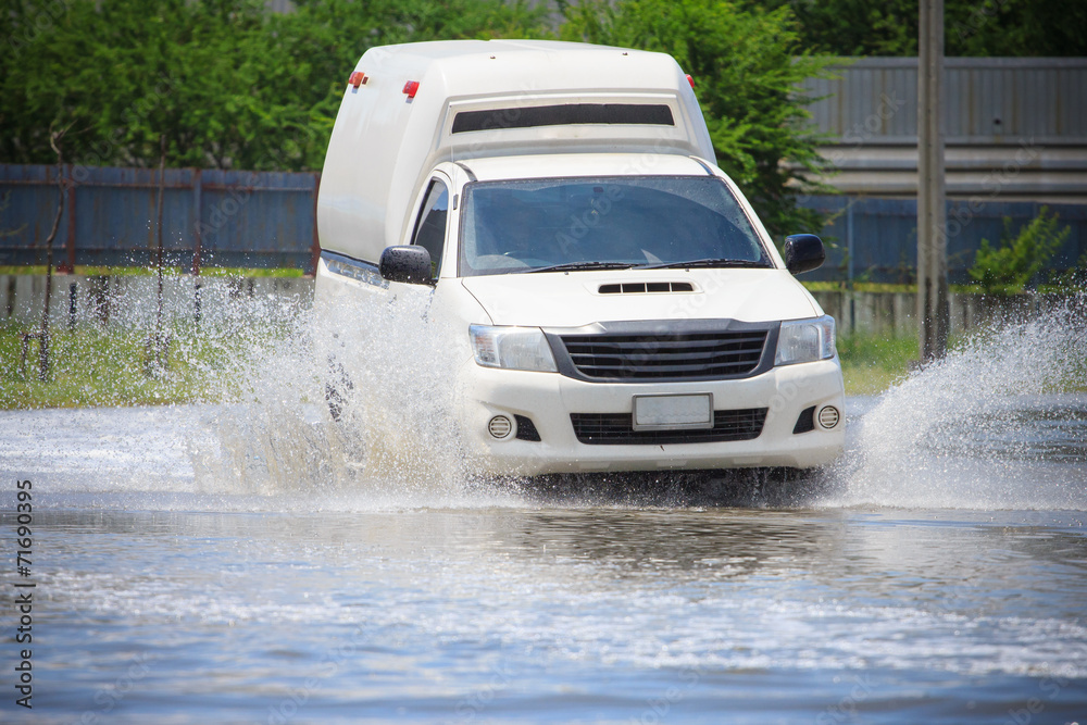 Splash by a car as it goes through flood water Splash by a car as it goes through flood water