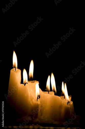 Group of white candles burning in the dark