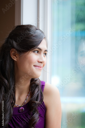 Beautiful biracial young woman smiling by window