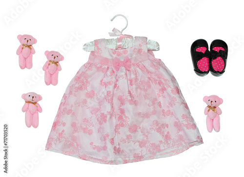 Pink dress isolated on white near shoes and toys.