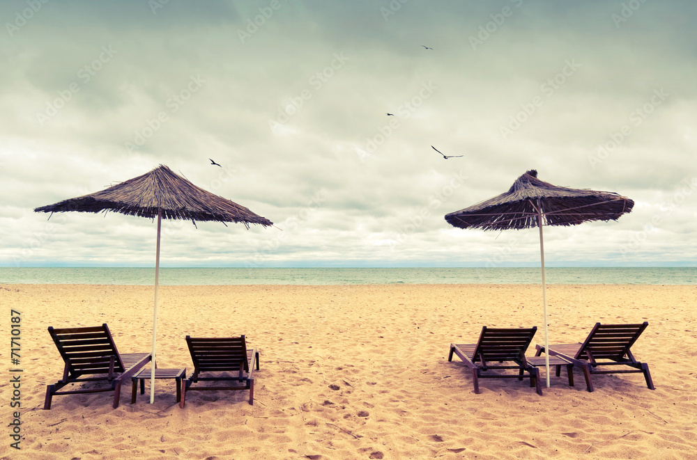 Sunbeds and umbrellas on empty sandy beach. Instagram toned phot