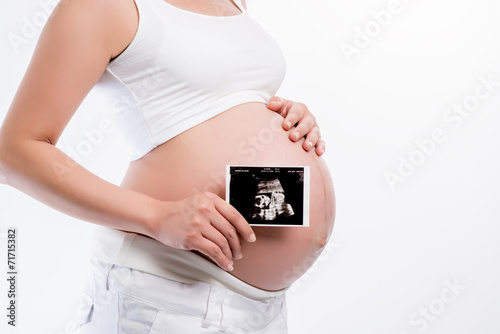 pregnant woman holding ultrasound scan on her tummy