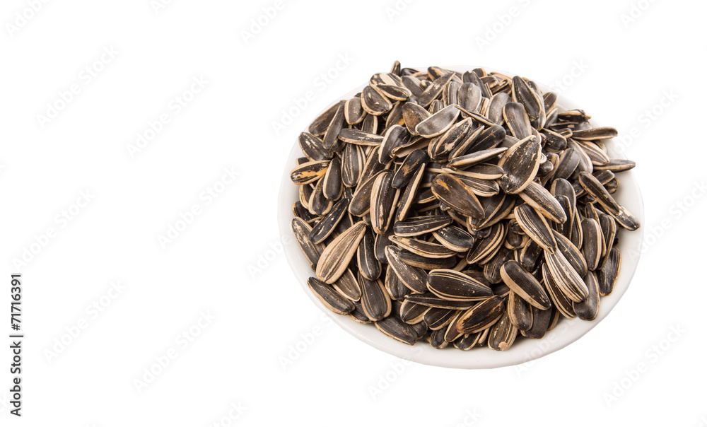 Sunflower seeds in white bowl over white background Sunflower seeds in white bowl over white background