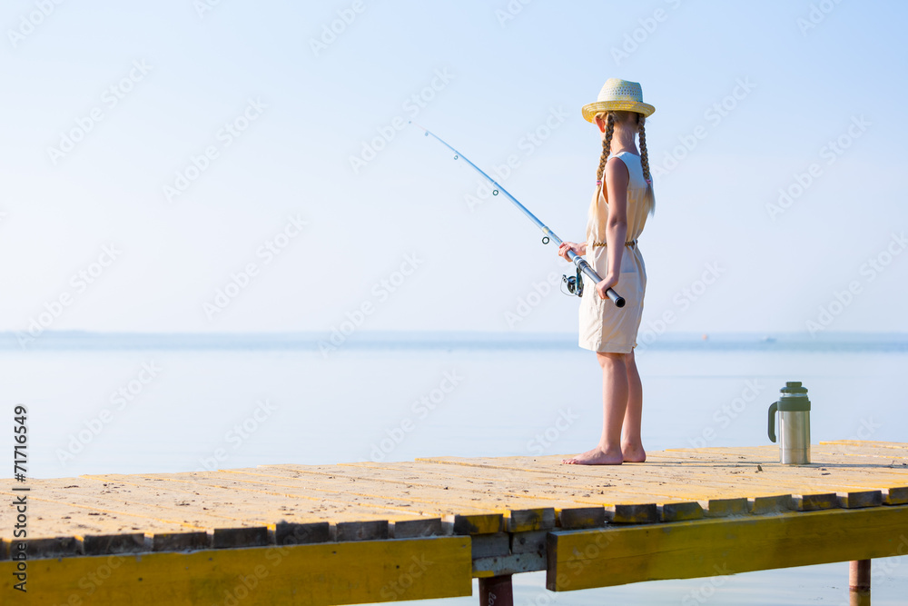 Girl in a dress and a hat with a fishing rod Girl in a dress and a hat with a fishing rod