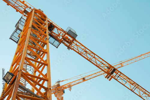 Modern yellow construction cranes above blue sky photo