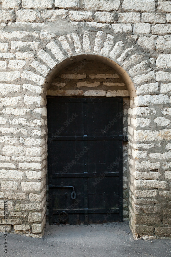 Old stone wall and black metal door, background texture