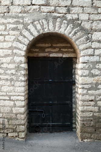 Old stone wall and black metal door  background texture