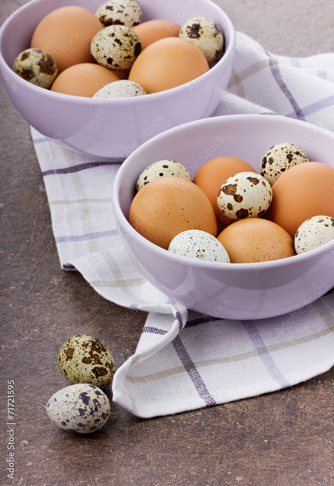 Chicken and quail eggs in a ceramic bowl on a brown surface Chicken and quail eggs in a ceramic bowl on a brown surface