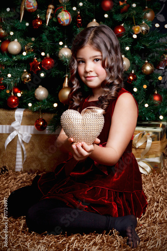 Pretty little girl holding a heart shaped Christmas ornament