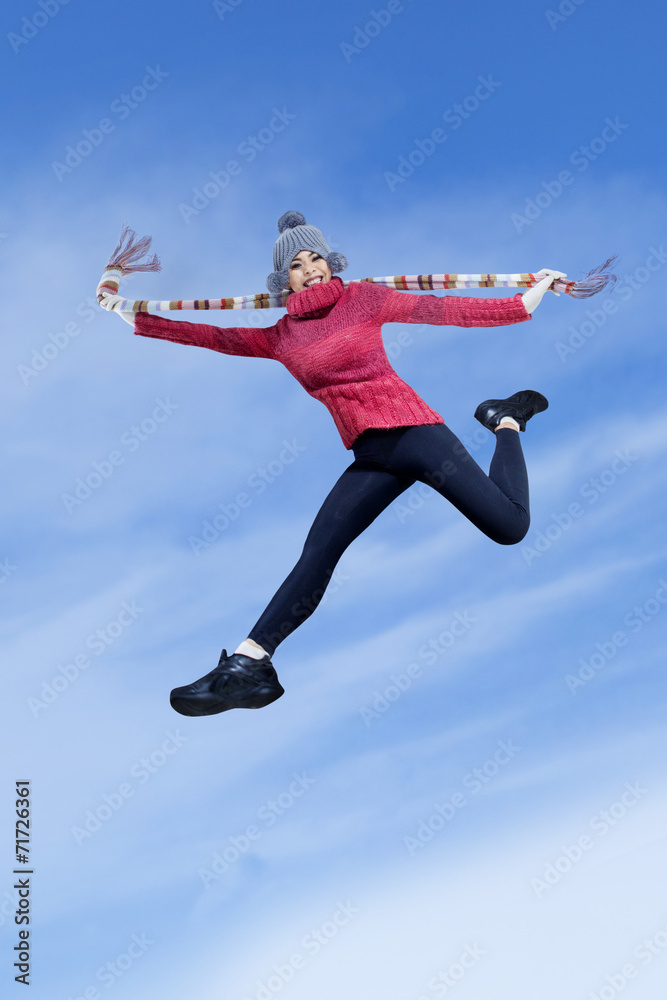 Happy girl jumping over blue sky