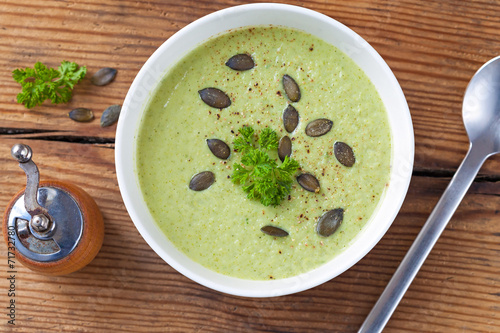 Homemade green broccoli cream soup served in white bowl photo