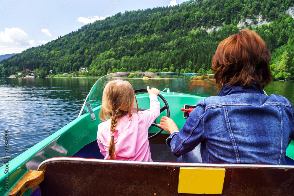 Fototapeta premium Little girl driving rental boat