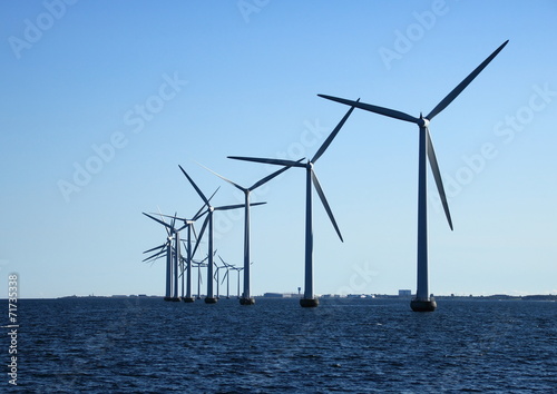 Perspective line of ocean windmills in back light